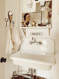 a white sink sitting under a bathroom mirror next to a shelf filled with towels and other items