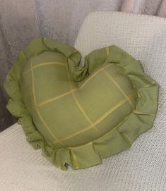 a green heart shaped pillow sitting on top of a white chair