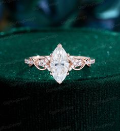 an engagement ring with a pear shaped diamond in the center on a green velvet box