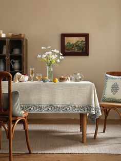 a dining room table with two chairs and a vase filled with flowers