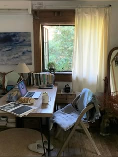 a laptop computer sitting on top of a wooden desk in front of a large window