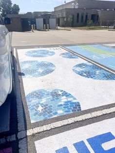 a car is parked in front of a parking lot with blue and white designs on it