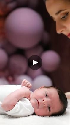 a baby laying on top of a bed next to a woman