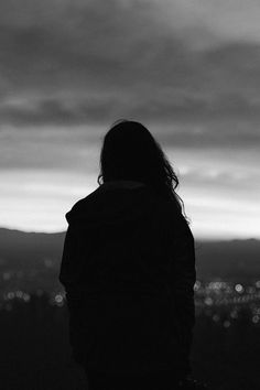 a person standing in front of a dark sky with the city lights behind them at night