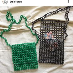 two pieces of art made out of wire on a white sheet with a green bag hanging from it