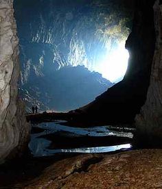 the light shines brightly in this cave with water running through it's entrance