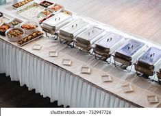 an assortment of buffet style food items on a long table with white linens and silverware