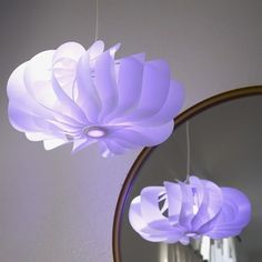 a mirror and some lights hanging from the ceiling in front of a light fixture that is shaped like a flower