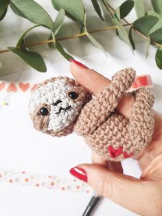 a hand holding a small crocheted slotty toy in it's palm