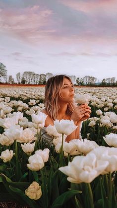 a woman sitting in a field of white tulips