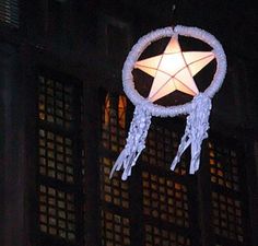 a white star hanging from the side of a building at night with lights on it