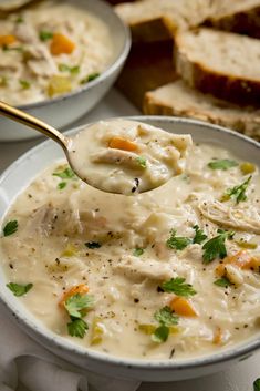 a spoonful of chicken and dumpling soup in a bowl with bread on the side