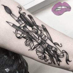 a woman's arm with some scissors and flowers on it next to her lips