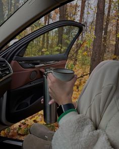 a woman holding a cup in her car