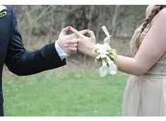 a man and woman standing next to each other holding hands with flowers in front of them