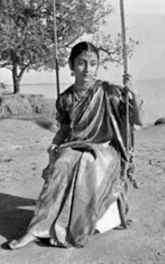 an old photo of a woman sitting on a swing