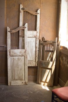 two old wooden doors sitting next to each other in a room with a red chair