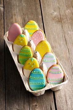 decorated easter eggs in an egg carton on a wooden table, ready to be eaten