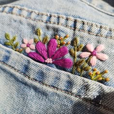 a pink flower is embroidered on the back of a pair of jeans