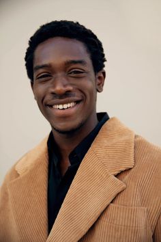 a man smiling and wearing a brown jacket