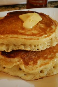 two pancakes with butter and syrup on a white plate