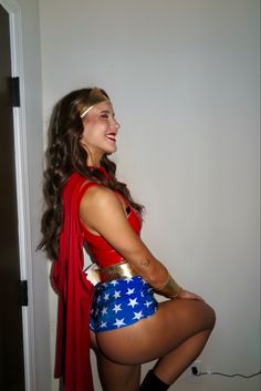 a woman in a red top and blue skirt posing for the camera with her legs crossed