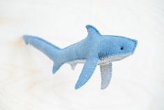 a blue stuffed shark hanging from a string