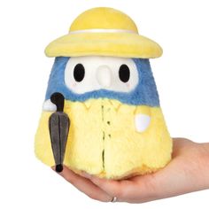 a hand holding a yellow and blue stuffed animal