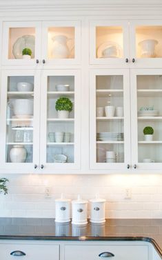 a kitchen with white cabinets and black counter tops, pots and pans on the shelves