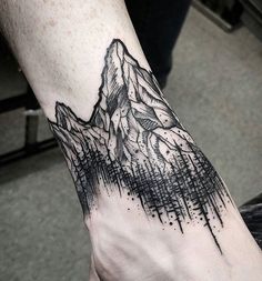 a hand with a mountain tattoo on it