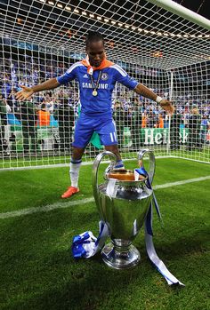 a soccer player standing next to a trophy