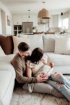 a man and woman are sitting on the floor with their baby