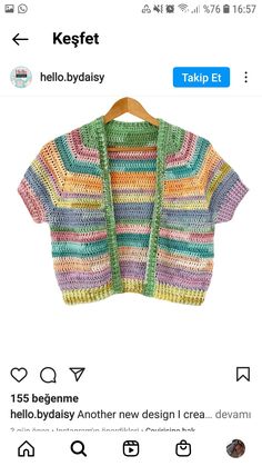 a colorful knitted cardigan sweater hanging on a wooden hanger in front of a tweet