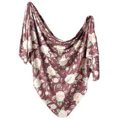 a pink and white flowered scarf hanging from a hook on a clothes line with the fabric draped over it