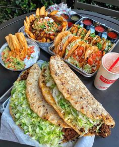 a table topped with trays of food and plates filled with different types of foods