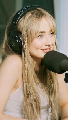 a woman wearing headphones sitting in front of a microphone