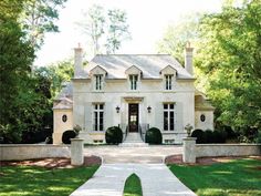 a large white house with lots of windows and bushes around the front door, on a sunny day