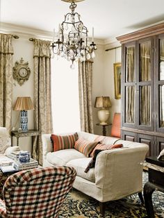 a living room filled with furniture and a chandelier hanging from the ceiling next to a window