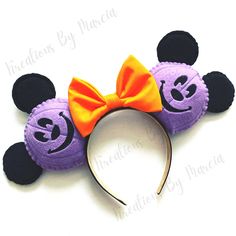 a purple mickey mouse ears with an orange bow on it's head and black ears