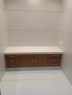 an empty white room with wooden cabinets and drawers