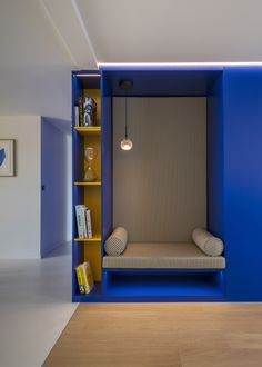 a room with blue walls and a bench in the corner, next to a book shelf