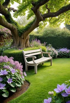 a wooden bench sitting in the middle of a lush green field next to a tree