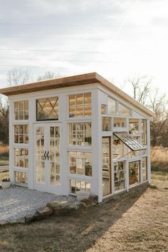 a small white building with lots of windows on the front and side of it's roof