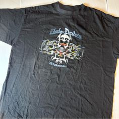 a black t - shirt with an image of a skull on the front and two skulls on the back