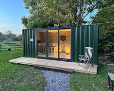 a small green cabin with sliding glass doors