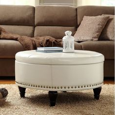 a white ottoman sitting on top of a rug in front of a couch and coffee table