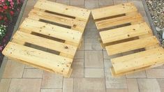 two wooden pallets sitting next to each other on a brick walkway with flowers in the background