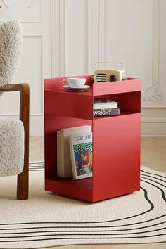 a red side table with magazines and a cup on it