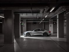 a car is parked in an empty parking garage with no one around it and the lights on