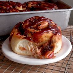 a bun covered in bbq sauce sitting on a plate next to a baking pan